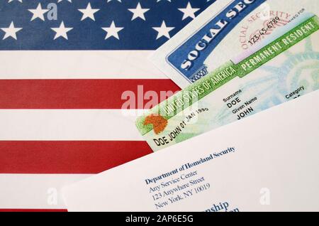 Les États-Unis résident permanent carte verte de dv-loto avec numéro de sécurité sociale se trouve avec l'enveloppe USCIS sur le drapeau américain de près Banque D'Images