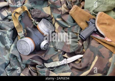 Les soldats stacker masque à gaz soviétique se trouve avec un pistolet et un couteau sur des vestes de camouflage kaki vertes. Kit post-apocalypse Surviving items Banque D'Images