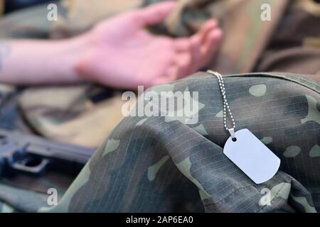 Un jeton militaire vide de soldat militaire mort se trouve sur des vêtements de camouflage. Suicide pendant le service militaire dans le concept de l'armée russe Banque D'Images