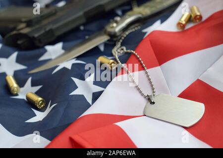 Jeton d'étiquette de chien de l'armée avec balles de 9 mm et pistolet se trouve sur le drapeau américain replié. Un ensemble d'articles anciens combattants militaires américains ou de trophées de vieux devoir Banque D'Images