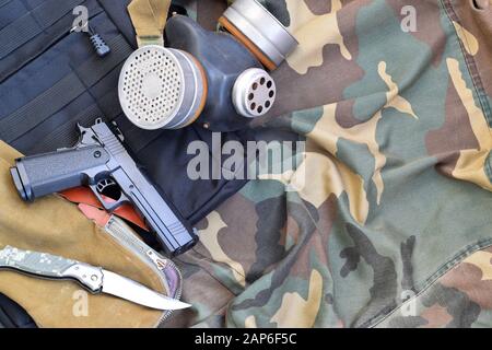 Les soldats stacker masque à gaz soviétique se trouve avec un pistolet et un couteau sur des vestes de camouflage kaki vertes. Kit post-apocalypse Surviving items Banque D'Images