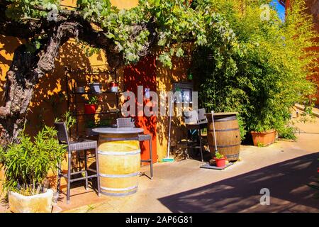 Roussillon En Provence, France - 2 Octobre. 2019: Vue sur la maison méditerranéenne d'ocre rouge avec de la vigne grimpant la façade, des tonneaux de vin et des arbres en soupir Banque D'Images