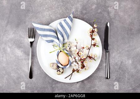 Magnifique table de Pâques avec œufs en serviette lapin de Pâques et branches fleuries sur fond de pierre. Vue de dessus. Banque D'Images