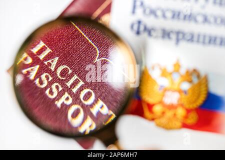 Passeport russe sous une loupe avec la Constitution de la Fédération de Russie sur fond blanc Banque D'Images