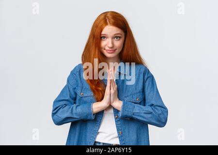 Taille-up portrait mignon et ridicule fille à tête rouge regardant l'espoir et le vœu appareil photo, demandant quelque chose, ont la faveur de demander, appuyez les mains ensemble la poitrine Banque D'Images