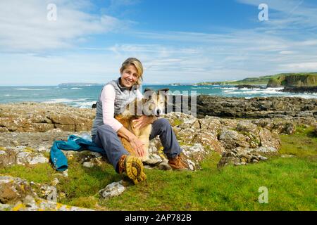 Une femme d'âge moyen en plein air en pleine santé marche sur Ulster Way avec le chien collie à la frontière. Les géants Causeway Coast à Dunselick, Co. Antrim, N. Ireland Banque D'Images