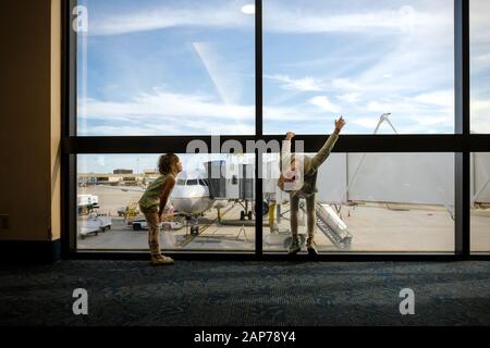 deux filles s'ennuient et jouent à l'aéroport en attendant de monter à bord de l'avion Banque D'Images