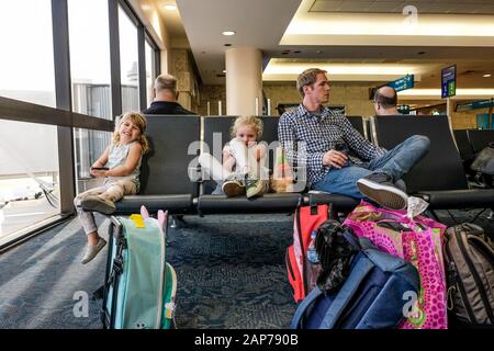 deux filles et un père assis dans le terminal de l'aéroport attendent de monter à bord Banque D'Images