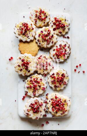 Sugar Cookies sans gluten avec glaçure sans oeufs décorés de graines de grenade, des pétales de rose et à la pistache Banque D'Images