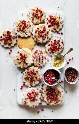 Sugar Cookies sans gluten avec glaçure sans oeufs décorés de graines de grenade, des pétales de rose et à la pistache Banque D'Images