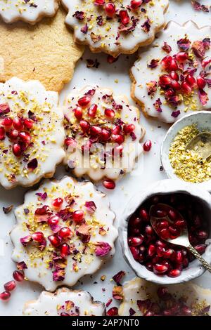 Sugar Cookies sans gluten avec glaçure sans oeufs décorés de graines de grenade, des pétales de rose et à la pistache Banque D'Images