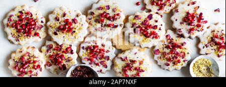 Sugar Cookies sans gluten avec glaçure sans oeufs décorés de graines de grenade, des pétales de rose et à la pistache Banque D'Images