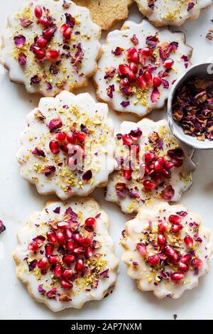 Sugar Cookies sans gluten avec glaçure sans oeufs décorés de graines de grenade, des pétales de rose et à la pistache Banque D'Images