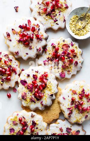 Sugar Cookies sans gluten avec glaçure sans oeufs décorés de graines de grenade, des pétales de rose et à la pistache Banque D'Images