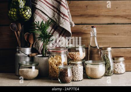 Concept de cuisine écologique : ustensiles de cuisine, plantes de maison, pommes en sac de coton, serviette en lin et ingrédients de cuisson dans des pots en verre contre Banque D'Images