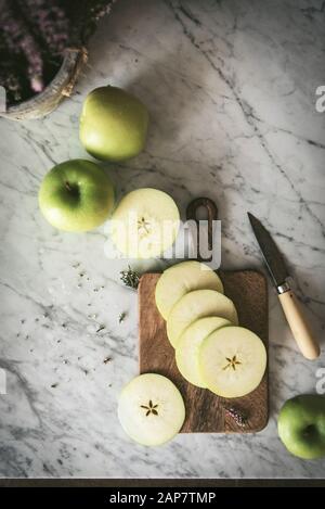 Pomme verte mûre fraîche, coupée en tranches sur une surface de travail dans une cuisine Banque D'Images