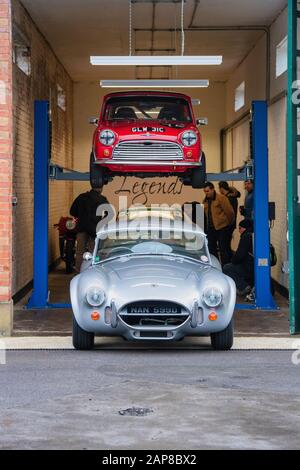 1966 AC Cobra et 1965 Morris Mini Cooper dans le garage Legends au Bicester Heritage Centre janvier événement de brouille du dimanche. Bicester, Oxfordshire, Royaume-Uni Banque D'Images