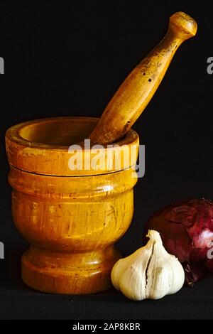 Toujours la vie: Mortier de bois avec pilon, ail, oignon rouge. Banque D'Images