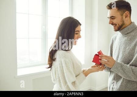 Le gars fait une proposition de mariage à la fille. L'homme souriant donne un anneau de proposition de mariage de dans la chambre. Banque D'Images