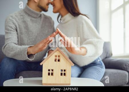 Mains de couple de famille tenant un modèle d'une maison Banque D'Images