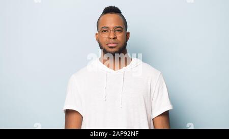 Portrait d'homme noir grave isolé sur fond bleu studio Banque D'Images