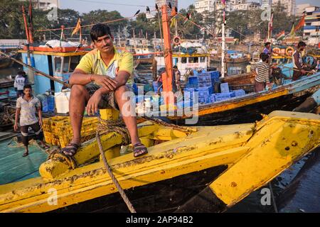 Un pêcheur assis sur son bateau de pêche ancré à Sassoon Docks, un port de pêche dans la région de Colaba, Mumbai, Inde Banque D'Images