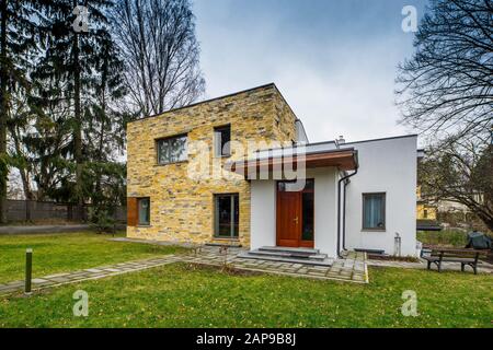 Un extérieur de maison privée moderne de deux étages. Porte d'entrée. Murs en briques jaunes. Murs blancs. Pelouse verte. Banque D'Images