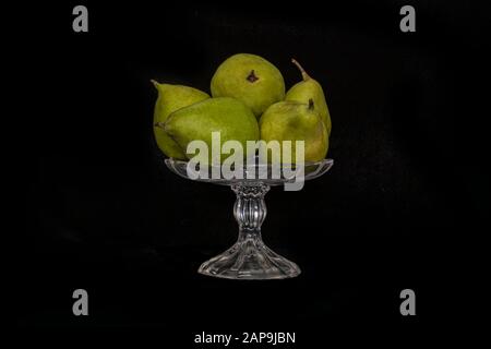 Toujours la vie. Poires mûres dans un vase en verre sur fond noir gros plan Banque D'Images