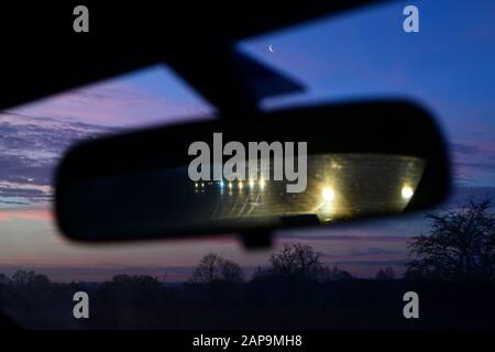 Les voitures se reflètent dans le miroir de l'aile du véhicule sur la chaussée double de l'A64 au lever du soleil avec un cadre de lune croissant au royaume-uni york Banque D'Images