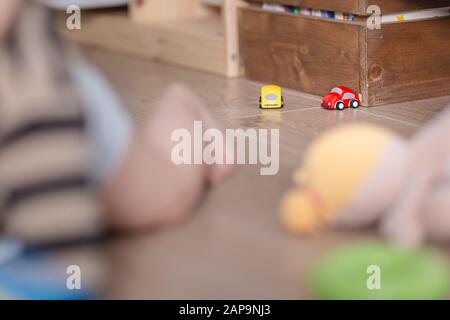 Petites voitures de jouet sur un plancher en bois avec bébé jouant avec eux Banque D'Images