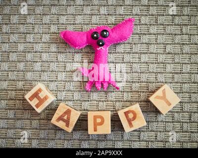 Jouet en bois faits main et chien alphabet blocks spelling heureux sur moquette grise. Jouets éducatifs pour les enfants en école maternelle. Banque D'Images