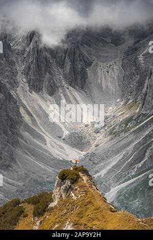 Mountaineer, femme debout sur une crête et regardant dans un cercle, nuages dramatiques, dans les parois rocheuses arrière de Cimon di Croda Liscia, Auronzo di Banque D'Images