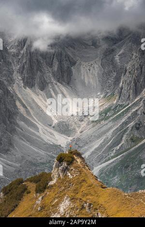 Mountaineer, femme debout sur une crête et regardant dans un cercle, nuages dramatiques, dans les parois rocheuses arrière de Cimon di Croda Liscia, Auronzo di Banque D'Images