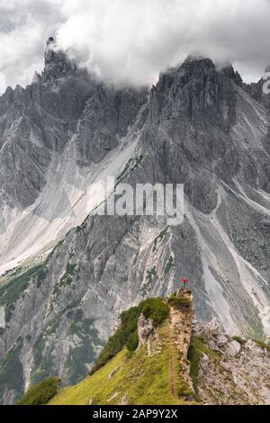 Mountaineer, femme debout sur une crête et regardant dans un cercle, nuages dramatiques, dans les parois rocheuses arrière de Cimon di Croda Liscia, Auronzo di Banque D'Images