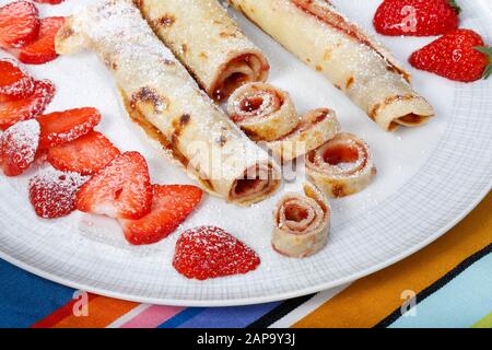 Dessert, crêpes fourrées à la confiture, sucre glace et fraises fraîches, roulées sur une assiette, Allemagne Banque D'Images