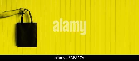 sac eco dans la main de mans sur fond jaune Banque D'Images