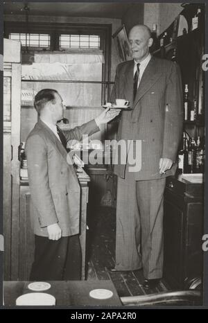 Albert J. Kramer, le plus grand homme au monde (2,42 m) dans son café au coin de Sloterkade et Theophile de Bockstraat à Amsterdam [a quitté son beau-frère] Date: 20 janvier 1955 lieu: Amsterdam, Noord-Holland mots clés: Cafés, hauteur, hommes Nom personnel: Kramer Albert J Banque D'Images