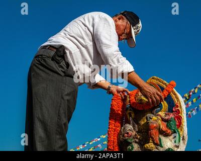 Homme local offrant une terre de fleurs à une image d'une aubaine à Boudha Stupa Banque D'Images