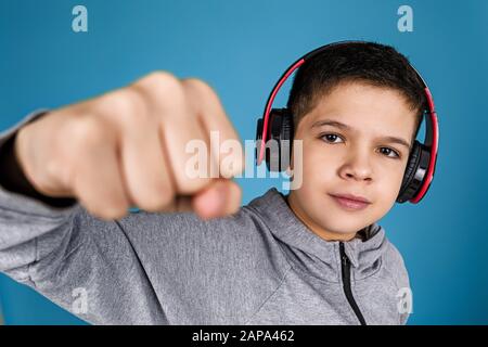 Garçon enfant bénéficie d'écoute de la musique dans les écouteurs sur fond bleu Banque D'Images