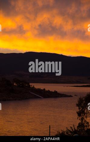 Des oranges lumineuses coucher de soleil au bord du lac Jindabyne dans les montagnes enneigées australie Banque D'Images