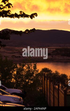 Des oranges lumineuses coucher de soleil au bord du lac Jindabyne dans les montagnes enneigées australie Banque D'Images