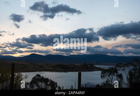 Des oranges lumineuses coucher de soleil au bord du lac Jindabyne dans les montagnes enneigées australie Banque D'Images