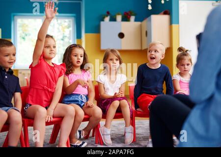Fille levant la main pour poser une question en classe Banque D'Images