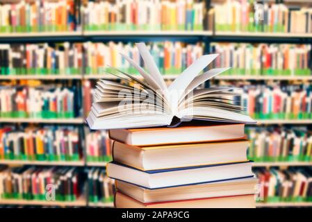Livre ouvert sur une pile devant une grande étagère Banque D'Images