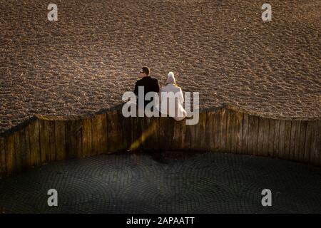 Couple assis sur la plage de Brighton manger et discuter Banque D'Images
