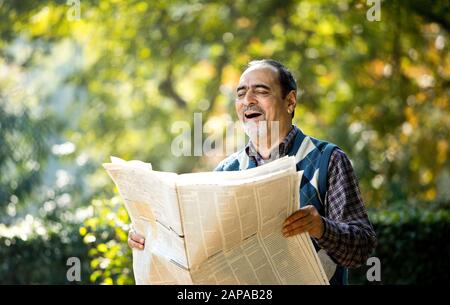 Homme senior lisant le journal dans le parc Banque D'Images