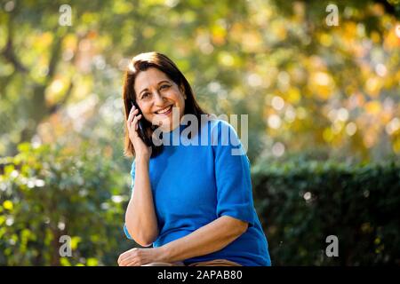 Heureuse femme senior messagerie texte à l'aide du téléphone mobile Banque D'Images