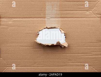 trou dans du papier en carton marron avec bords déchirés et incurvés. Modèle vide. Banque D'Images