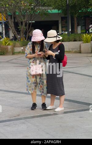 Les touristes asiatiques loking dans le téléphone mobile debout dans la rue, Chiang Mai Thaïlande Banque D'Images
