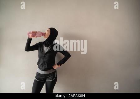 les femmes asiatiques sportives hijab portent des vêtements de sport lorsqu'elles boivent des bouteilles d'eau Banque D'Images